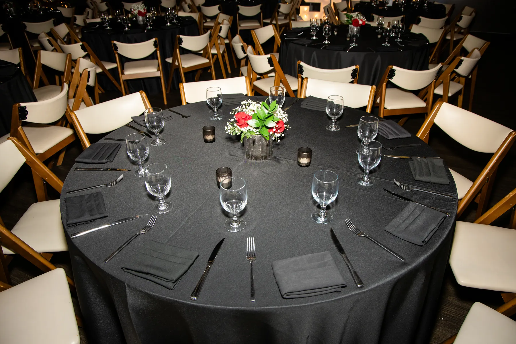 Place setting detail — centerpiece, glassware, and folded napkins under candlelight at the SQA holiday dinner